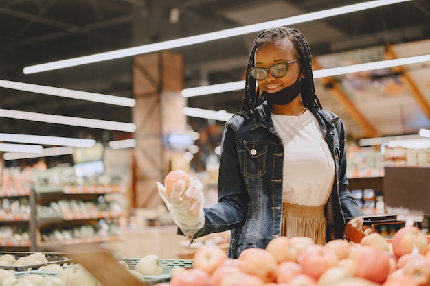 Ragazza nera con una maschera compra un cibo