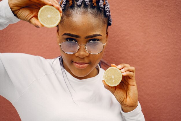 Black girl standing on a wall backgroung with a lemons