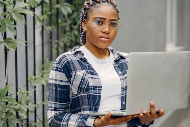 Black girl in a summer city with laptop