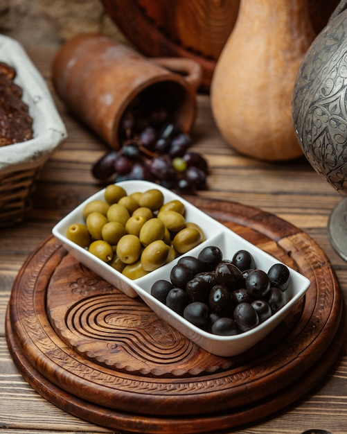 Olive marinate nere e verdi in ciotola bianca.