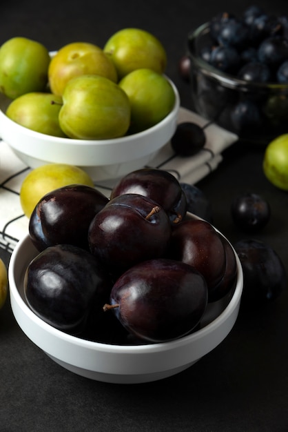 Free photo black and green plums in white ceramic saucer in the kitchen