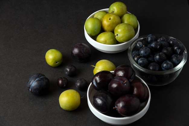 Black and green plums in white ceramic saucer