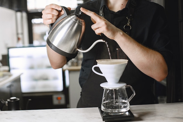 黒挽いたコーヒー。バリスタは飲み物を醸造します。ガラスの水差しのコーヒー。