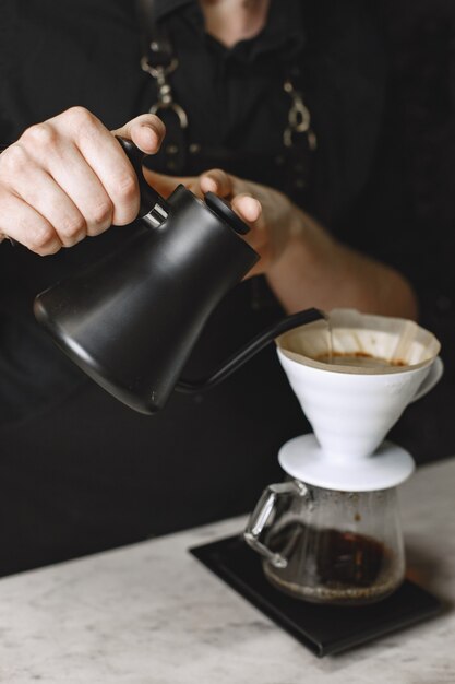 검은 가루 커피. 바리 스타는 음료를 양조합니다. 유리 용기에 커피.