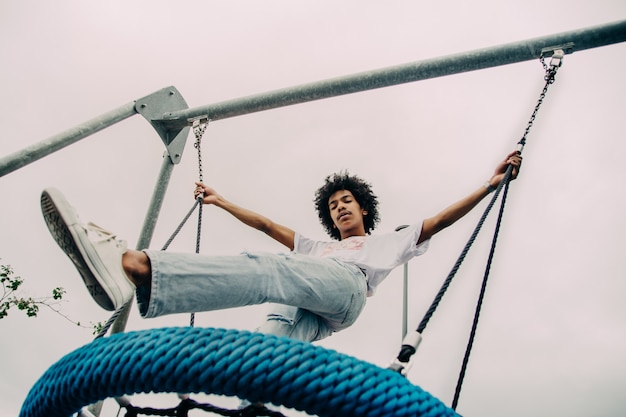 Black guy standing on a big swing