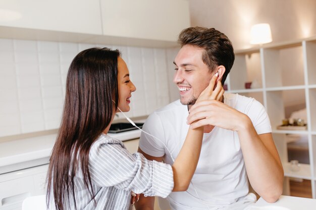 Black-haired tanned woman holding husband's face while talking with him