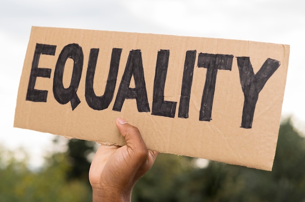 Free Photo black hand holding equality on cardboard