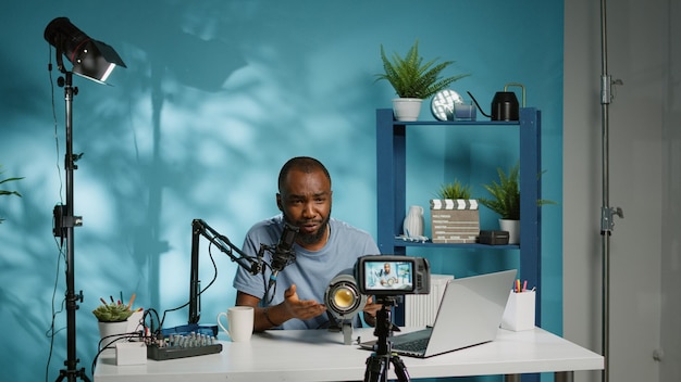 Черный влиятельный человек рассказывает о студийном свете для обзора видеоблога на камеру. Афроамериканский влогер просматривает профессиональный инструмент для видеосъемки, держит снаряжение для рекомендации