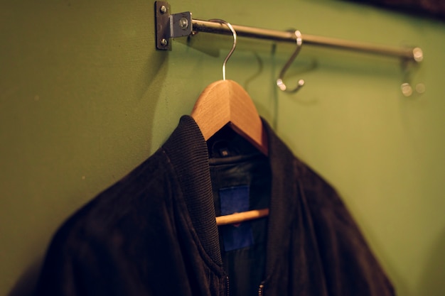 壁にレールに掛かっている木製ハンガーに黒いジャケット