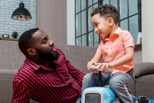 Free photo black little boy driving toy car with father