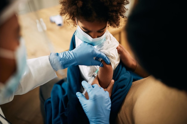 Bambina nera vaccinata presso l'ufficio del medico a causa della pandemia di coronavirus