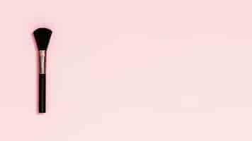 Foto gratuita pennello trucco nero su sfondo rosa