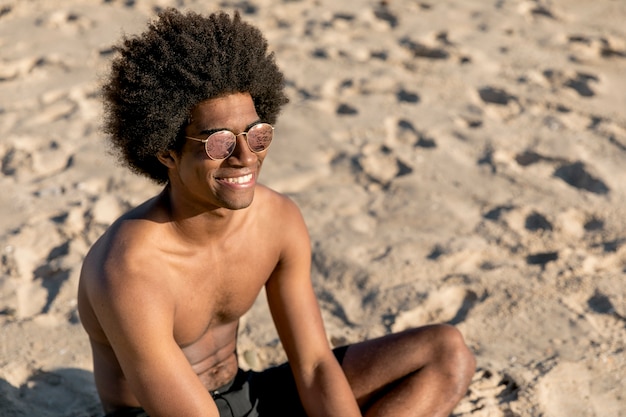 모래에 앉아 선글라스에 흑인 남성