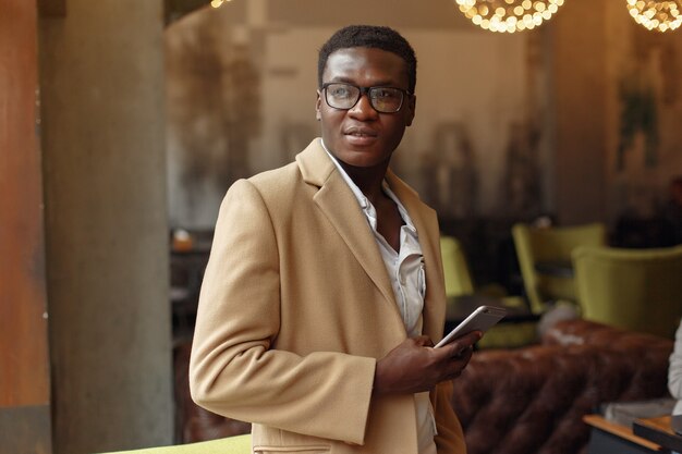 Black man in a brown coat standing with mobile phone