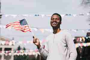 Free photo black man holding american flag and laughing