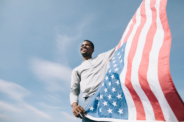 Foto gratuita bandiera americana d'ondeggiamento della holding dell'uomo di colore