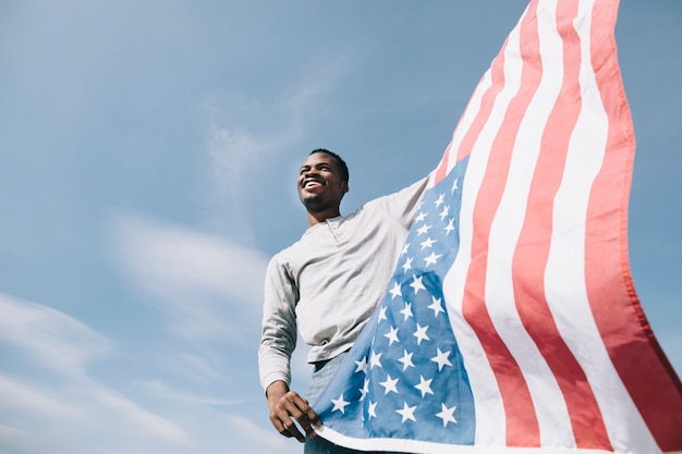 Черный человек держит развевающийся американский флаг