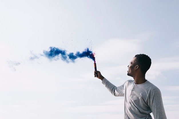 Black man raising colored smoke bombs 