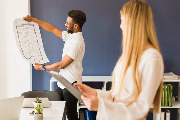 Black man showing blueprint to woman