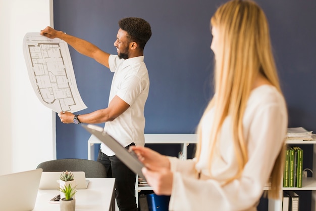 Black man showing blueprint to woman