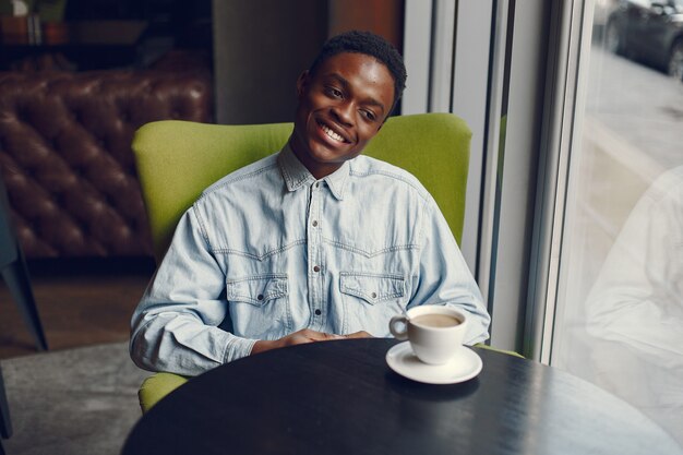 Black man sitting in a cafe and drinking a coffee