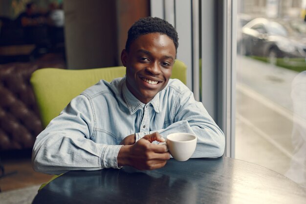 Black man sitting in a cafe and drinking a coffee