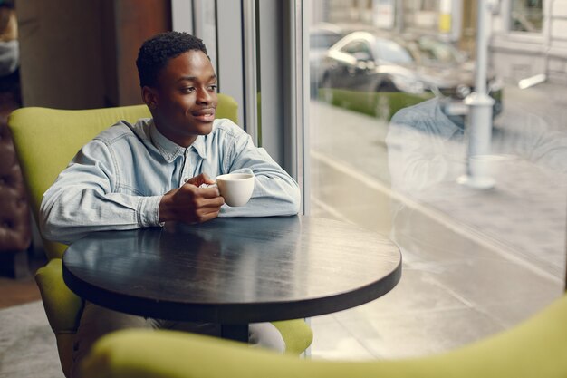 Black man sitting in a cafe and drinking a coffee