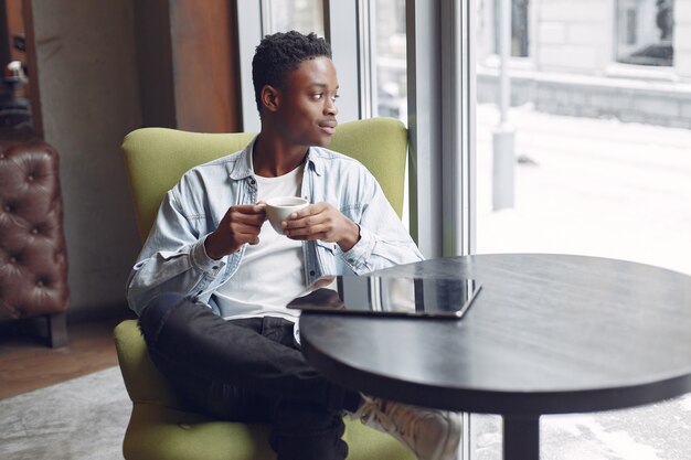 Black man sitting in a cafe and drinking a coffee