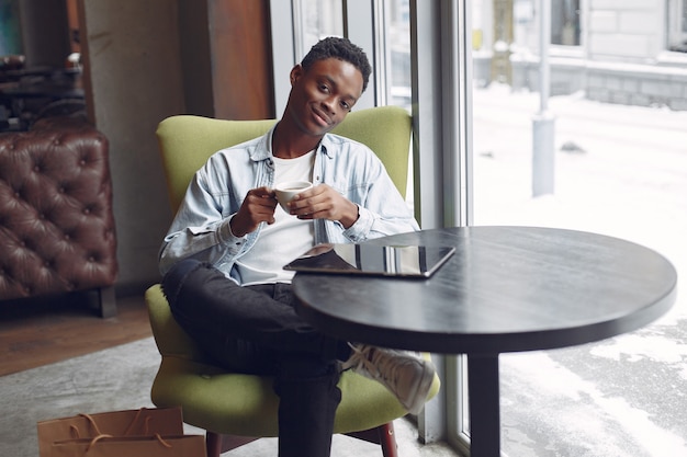 Black man sitting in a cafe and drinking a coffee