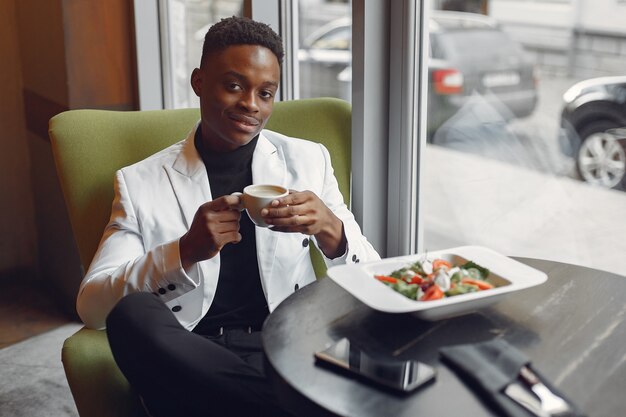 Black man sitting in a cafe and eating a vegetable salad