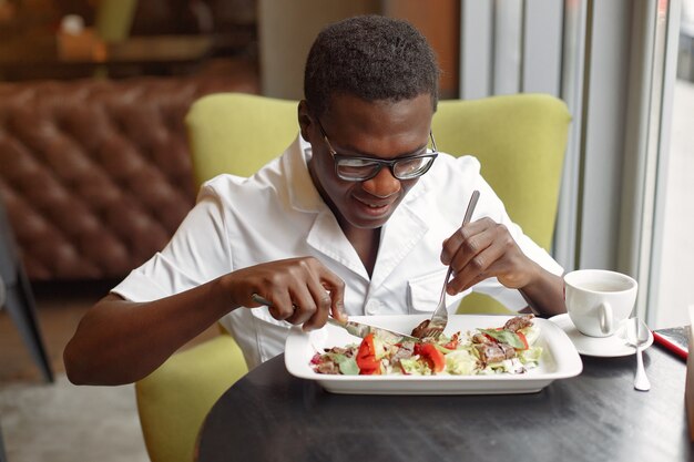 カフェに座っていると野菜のサラダを食べる黒人男性