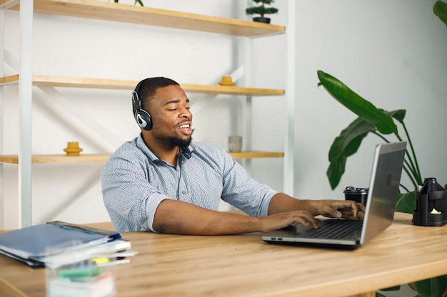 Black man sitting in office wearing a earphones and make a video call