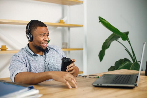 Black man sitting in office wearing a earphones and make a video call