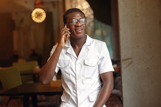 Black man standing in a cafe and use the phone