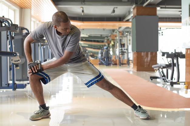 Black man stretching leg in gym