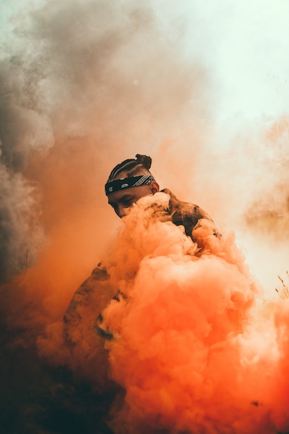 Free photo black man surrounded by orange smoke