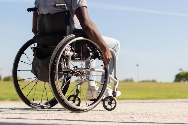 Black man in wheelchair riding along park road