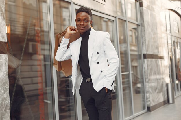 Black man in a white jacket with shopping bags