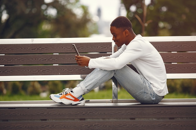 Black man in a white sweater in a summer city