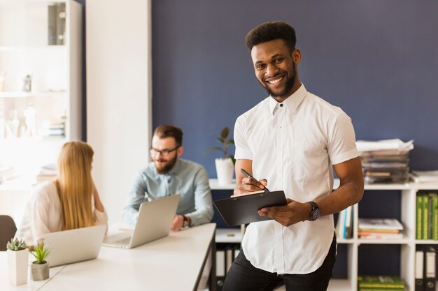 Black man with clipboard near colleagues