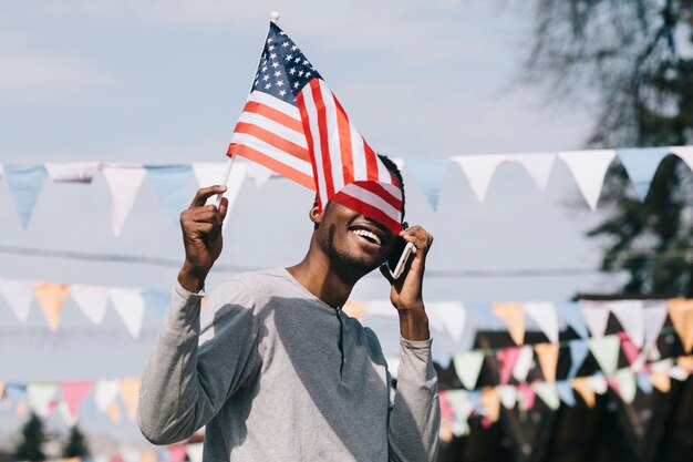 Uomo di colore con bandiera USA e smartphone