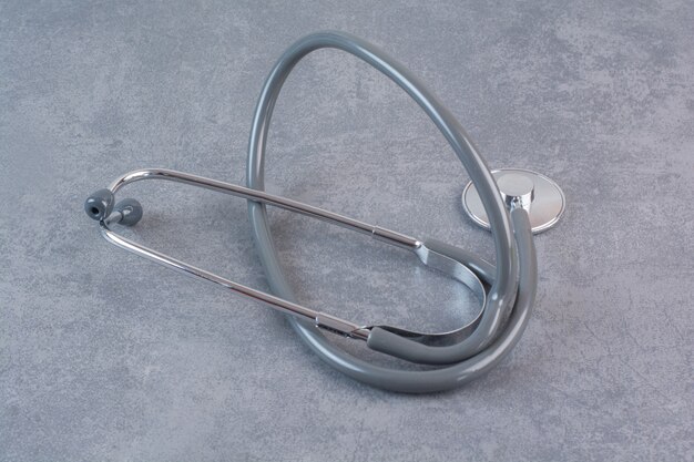 Black metal stethoscope on marble table.