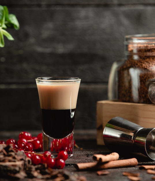 Black milky cocktail with berries and cinnamon sticks.