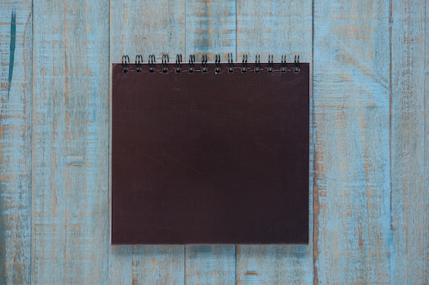 Black notebook on blue wood table 