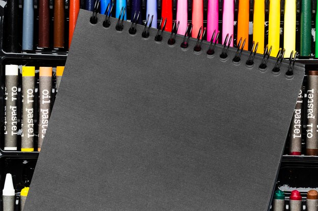 Black notepad and colourful markers and crayons