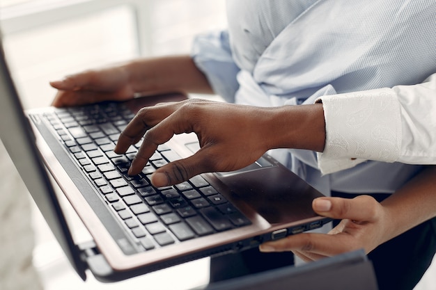 Free photo black people standing on a white wall with a laptop