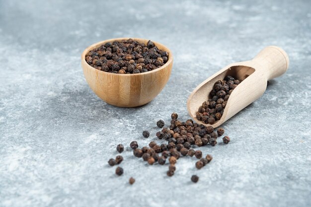 Black pepper grains on marble background.