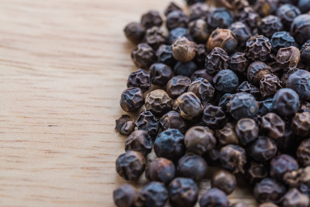 Black pepper on wood background