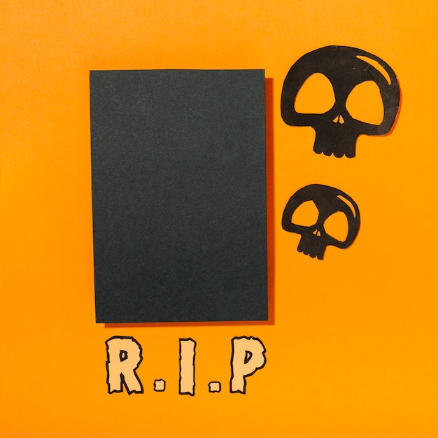 Free photo black piece of paper with skulls and r. i. p inscription