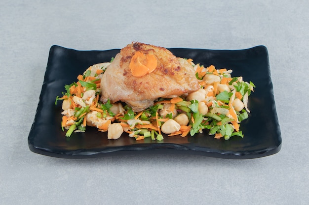 닭고기 튀김 고기와 야채 샐러드의 검은 접시.